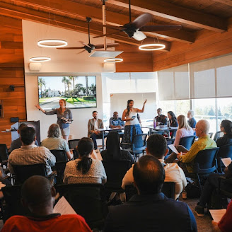 Two students presenting indoors in front of a full audience. Links to Social Justice Leadership EdD page.