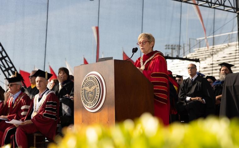SCU President Julie Sullivan speaking at a podium.