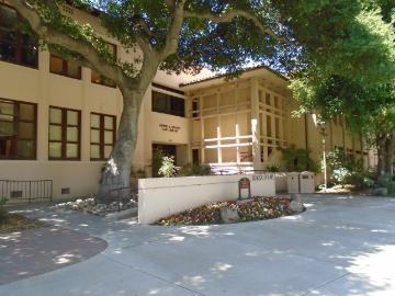 Entrance of Heafy Law Library with tree shade and outdoor seating area.