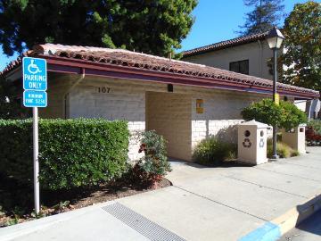 Outdoor restroom building with a tiled roof and surrounding greenery.