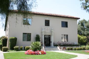Two-story building labeled Varsi Hall with trees and landscaping in front.