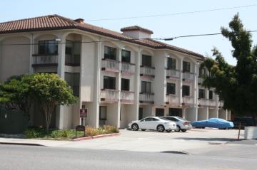 Bellarmine Hall building with parked cars in front and trees around.