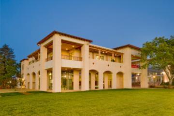 Two-story modern house exterior at dusk with large windows and balconies.