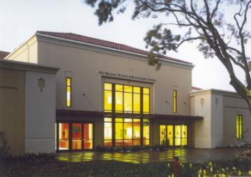 Pat Malley Fitness Center at Santa Clara University with illuminated windows and tree in foreground.