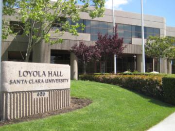 Loyola Hall building sign, surrounded by greenery and trees.