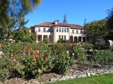 Large white house with garden and flowers in the foreground.