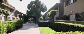 Two-story residential buildings lining a landscaped courtyard with trees and shrubs.