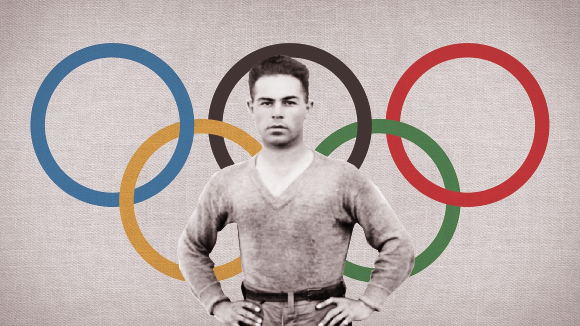 A black and white photo of a man standing in front of the Olympic rings in color