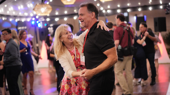 A woman and a man smiling and dancing on a dancefloor