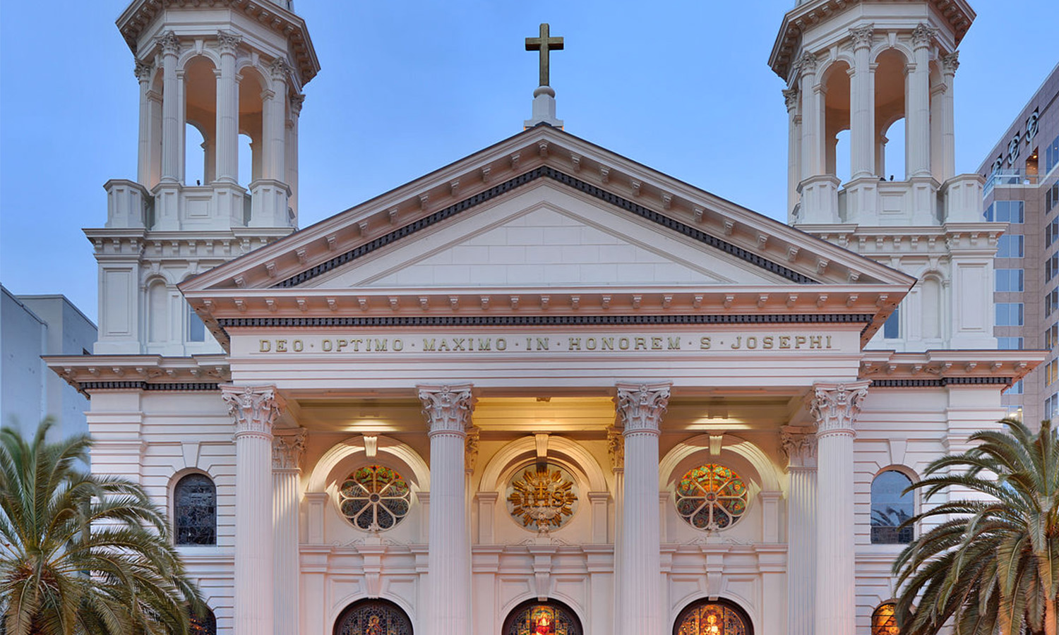 Alt text: Stately cathedral with twin bell towers and illuminated façade.