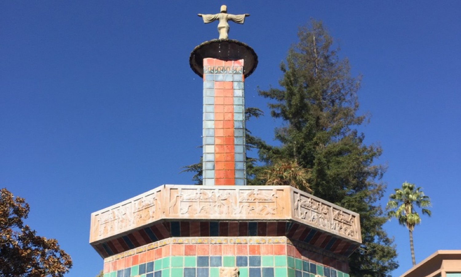 A hexagonal building with a cross atop a tall column.