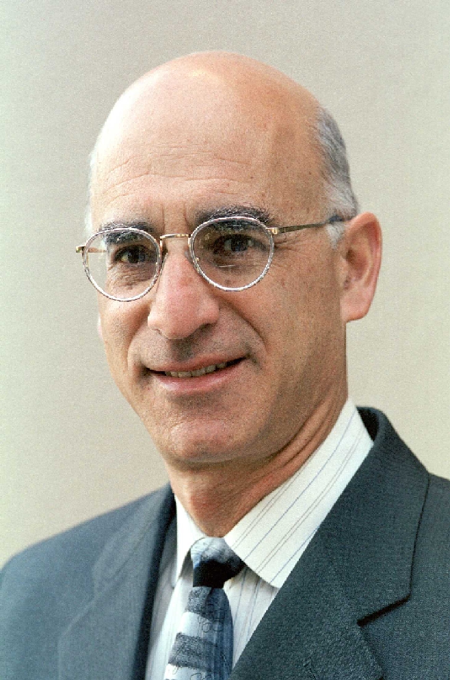A person wearing a suit and glasses, named Daniel Pitt.