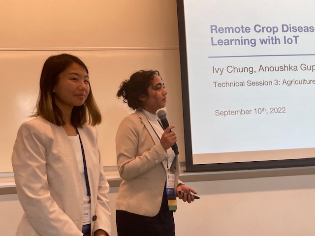 Two people presenting in front of a projection screen titled 