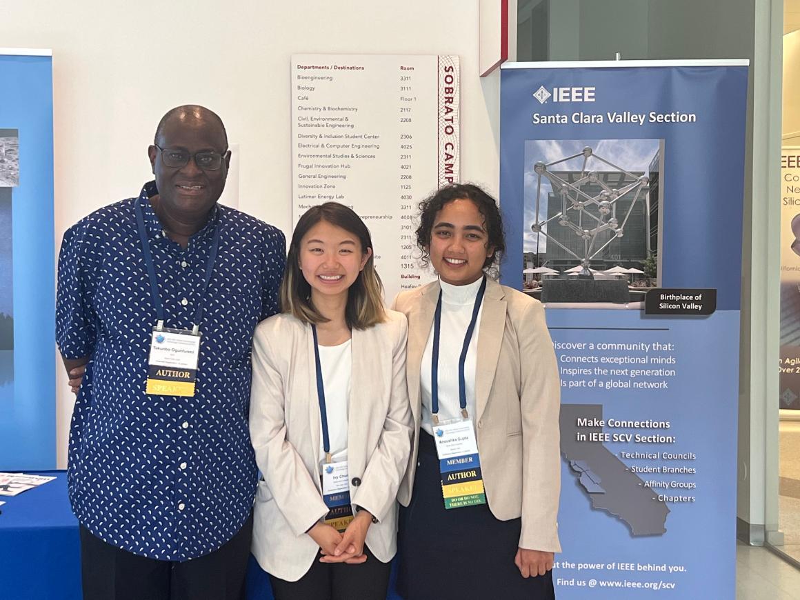 Three people posing together at GHTC 2022 conference booth.