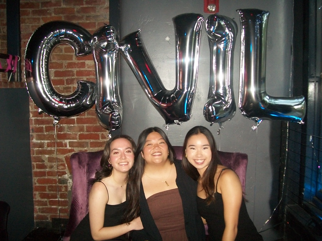 Three girls posing in front of balloons spelling out 