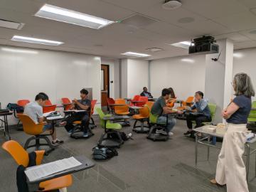 Students engaged in a mock negotiation with professor watching